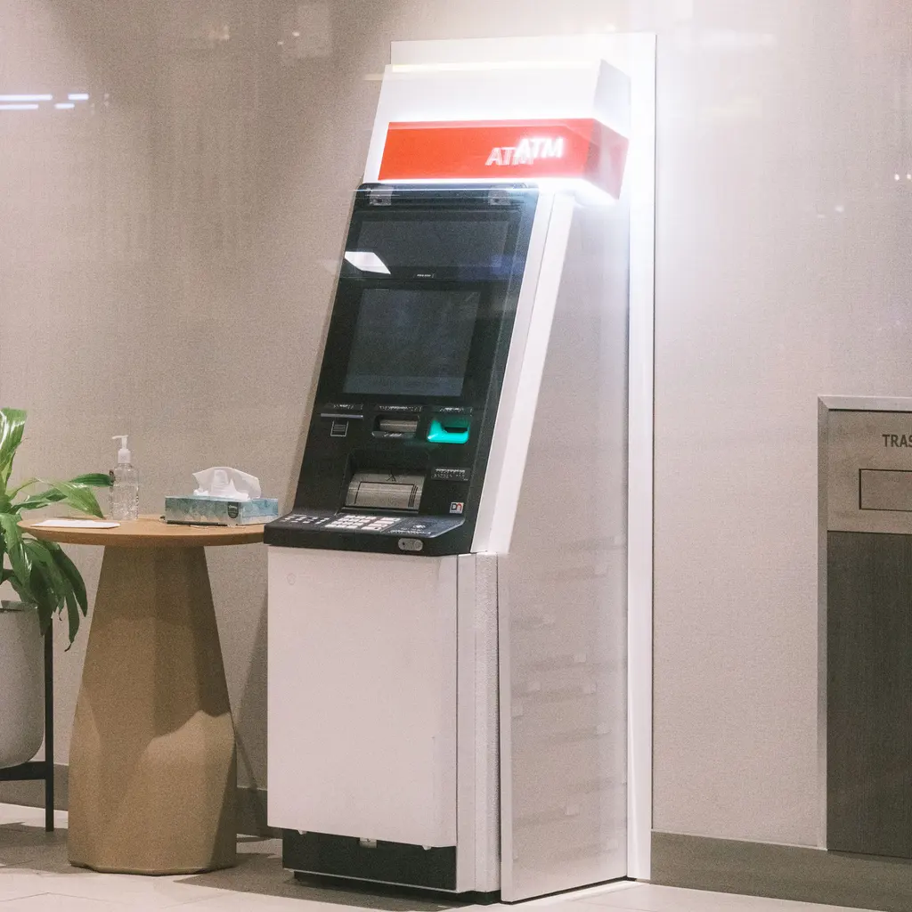 An ATM beside a service counter inside a financial branch.