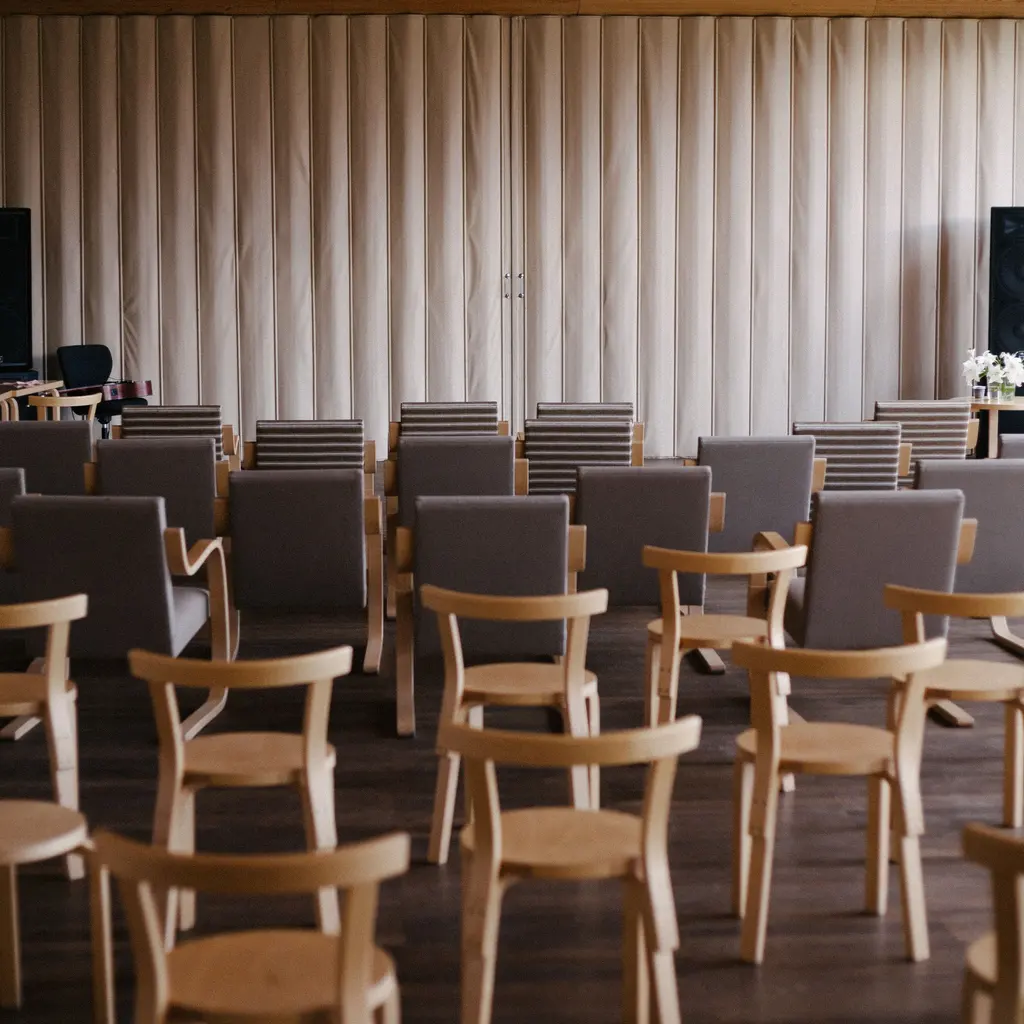 Rows of wooden chairs facing a curtained presentation area.