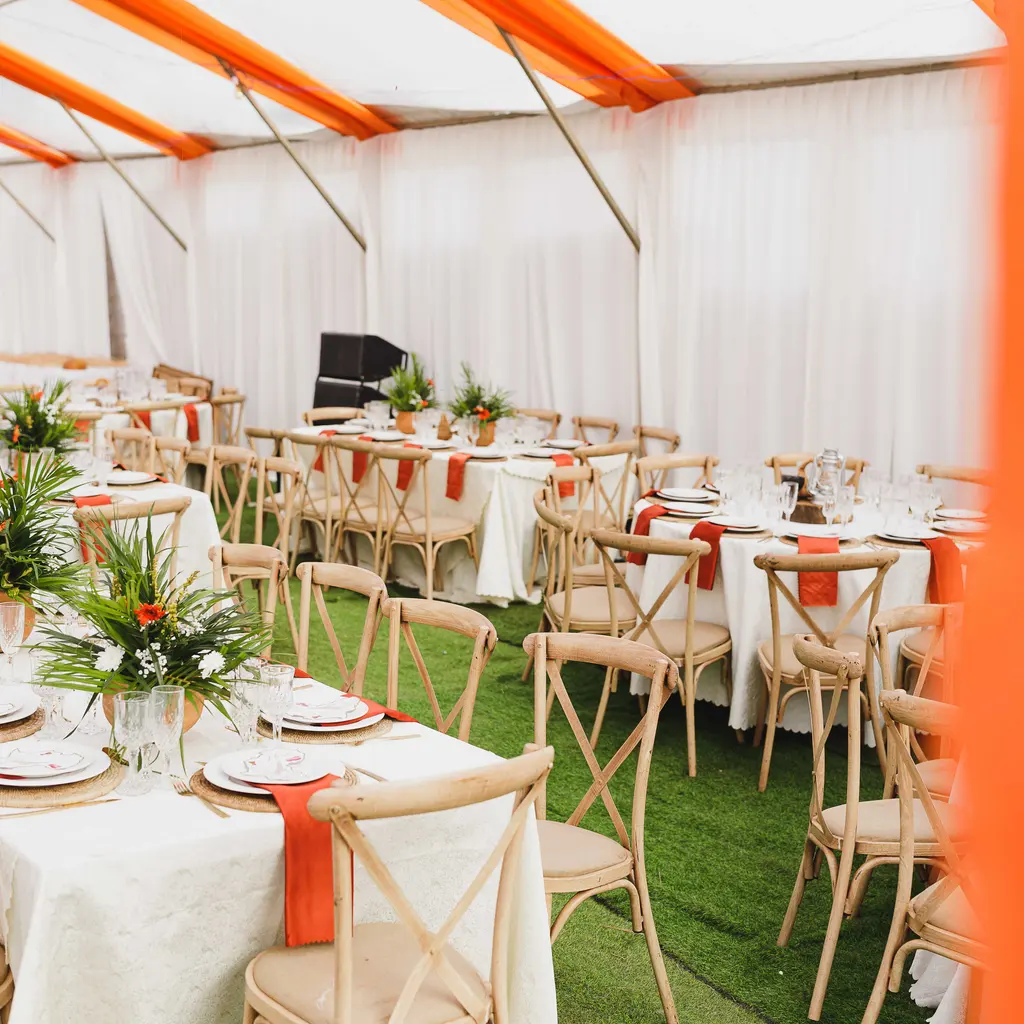 Event tables and chairs arranged beneath a large white-and-orange marquee.