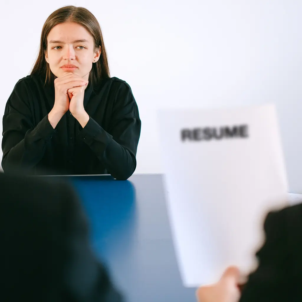 A candidate seated across from interviewers reviewing a résumé.