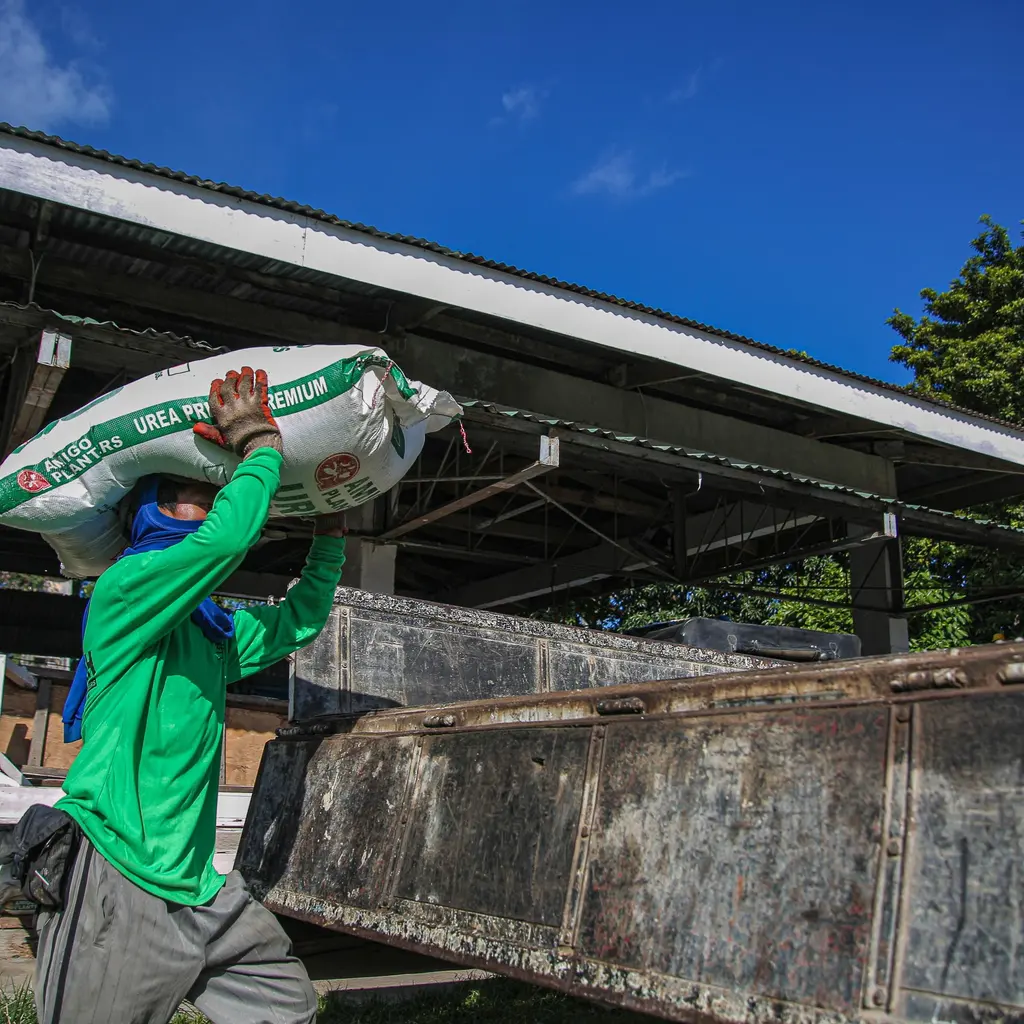 A worker loading a large bag beside a delivery truck.