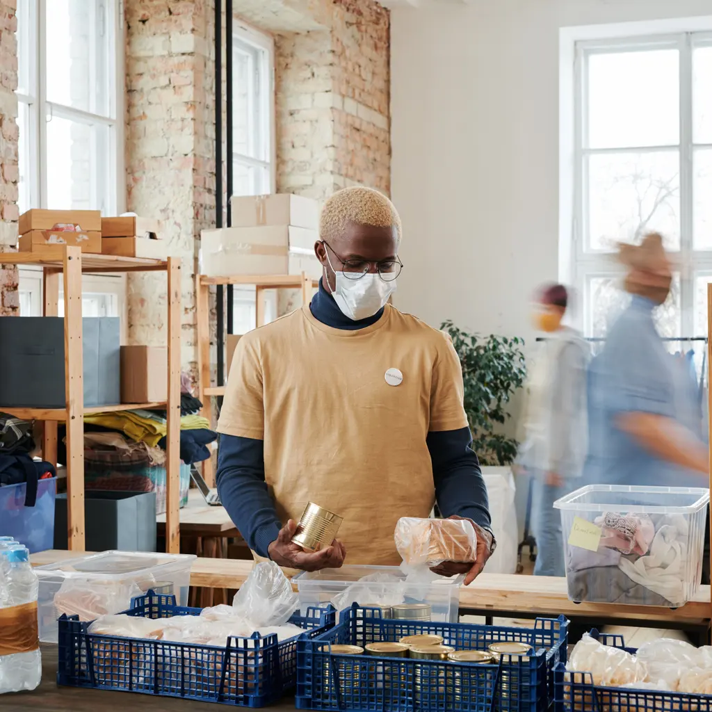 A worker sorting packaged food into crates at a donation-packing station.