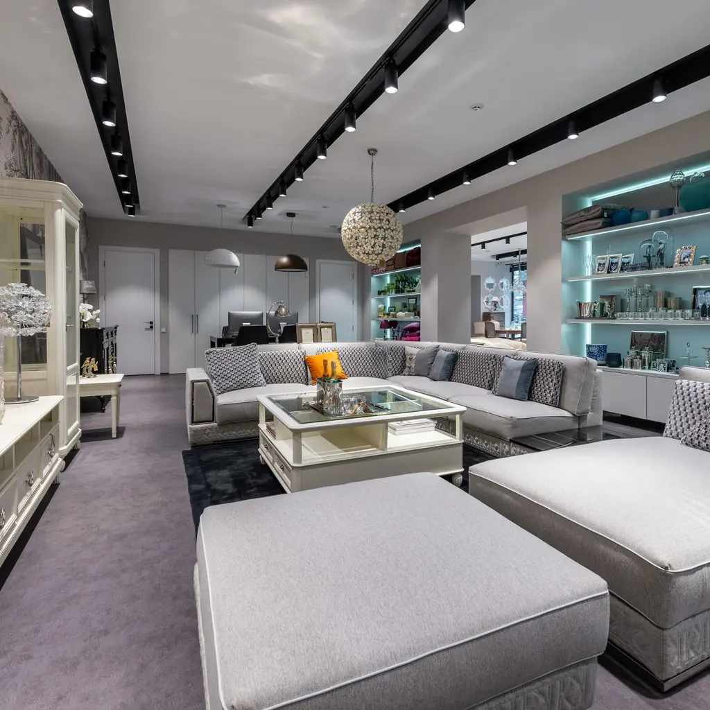 A gray sectional sofa, matching ottoman and glass coffee table arranged in a furnished room.