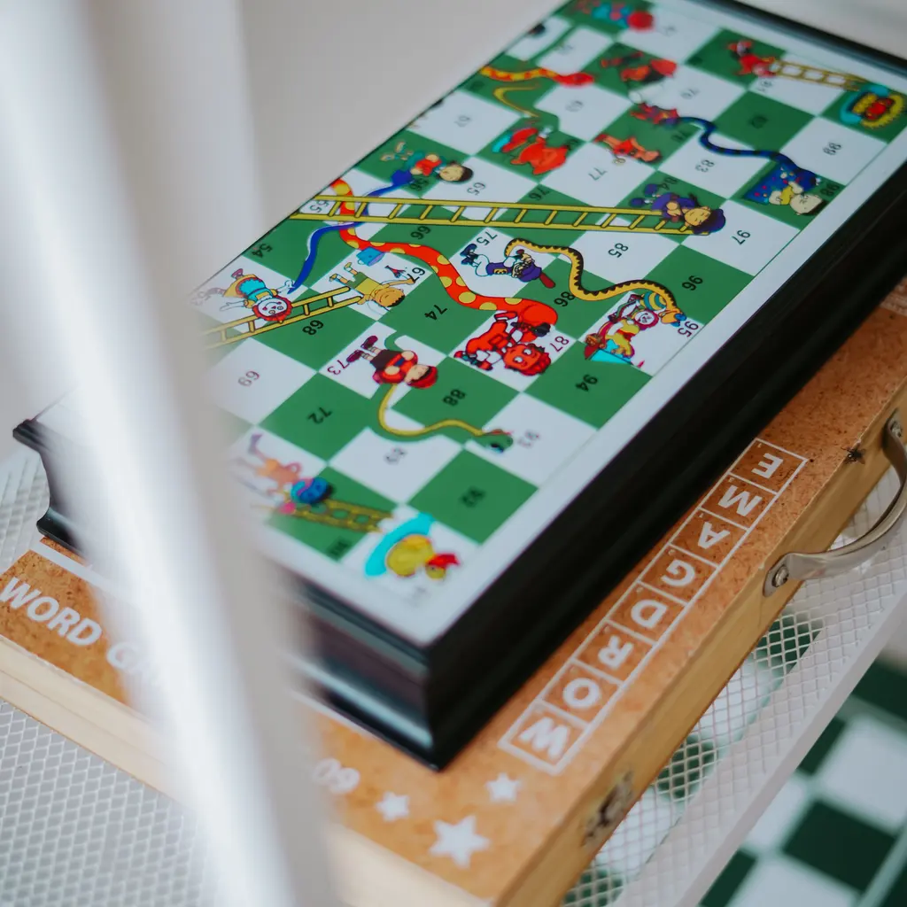 A colorful board game resting on a stack of game boxes on a shelf.