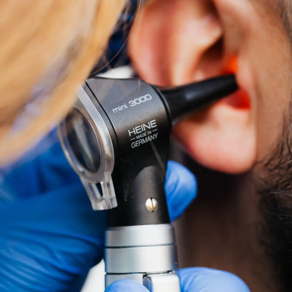 An otoscope positioned beside an ear during an examination.