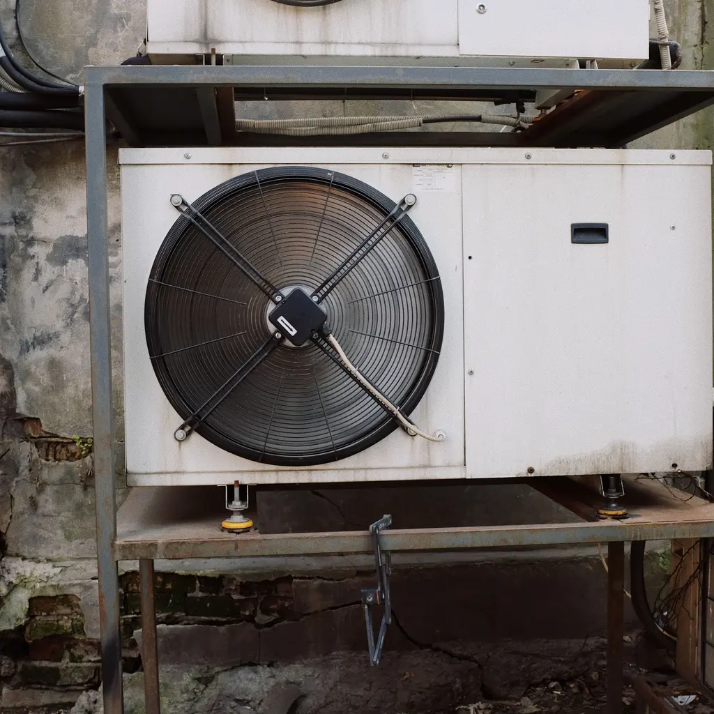An outdoor condensing unit with a large fan and white metal housing.