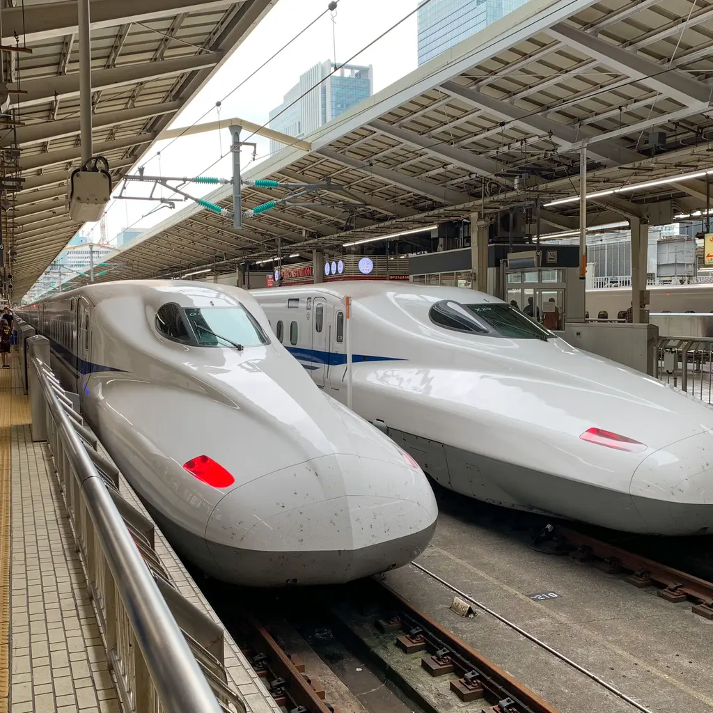 Two streamlined high-speed trains beside station platforms.