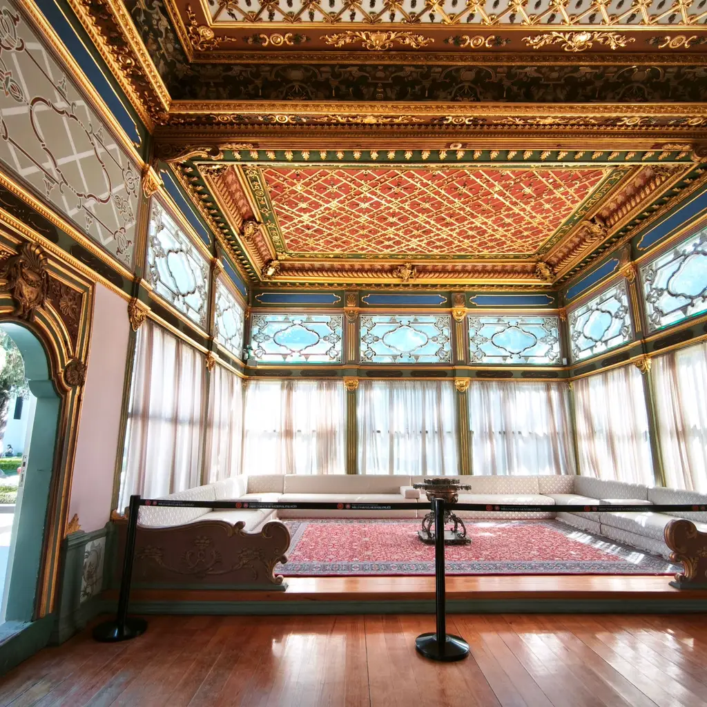 A roped-off historic room with period furnishings and an ornate ceiling.