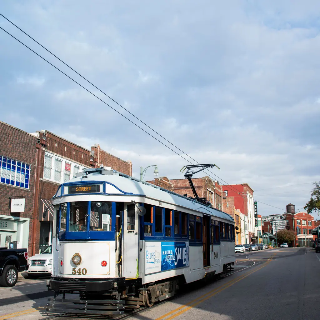 A vintage streetcar traveling along an urban street.
