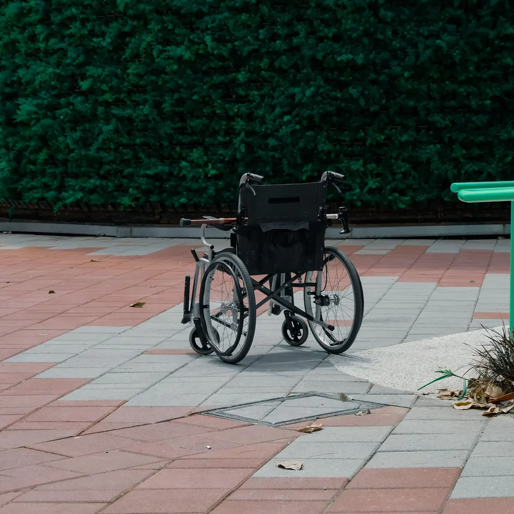 An empty wheelchair standing on a paved garden path.