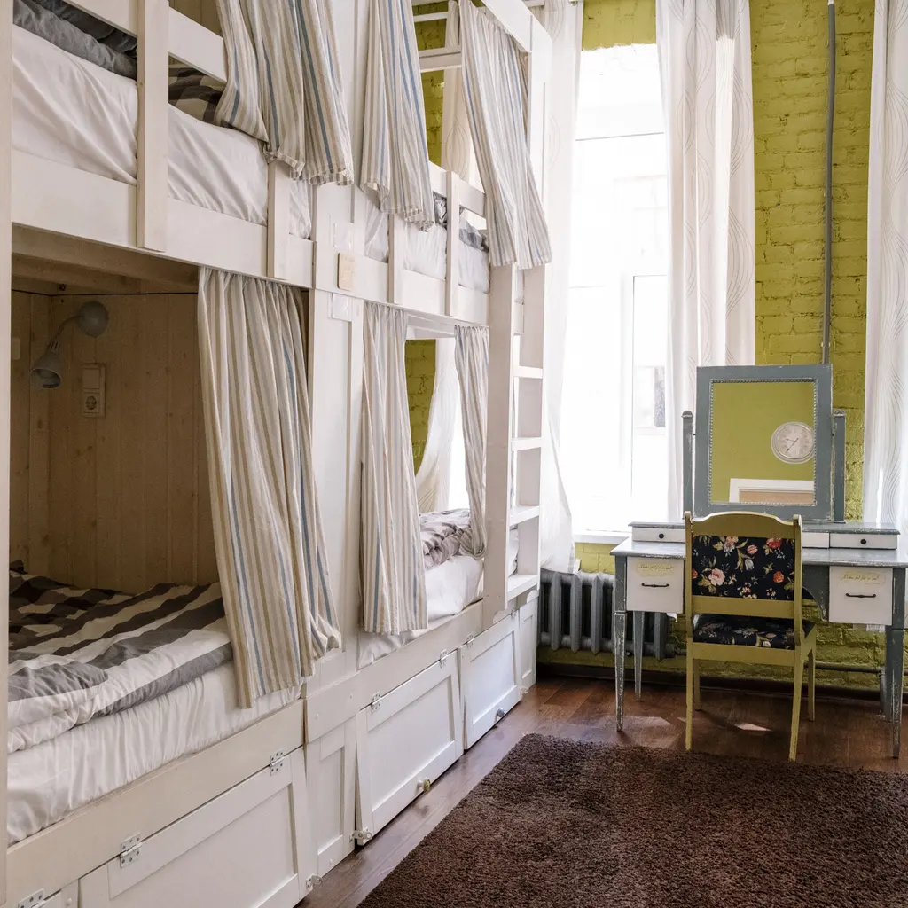 An empty shared sleeping room with bunk beds and privacy curtains.