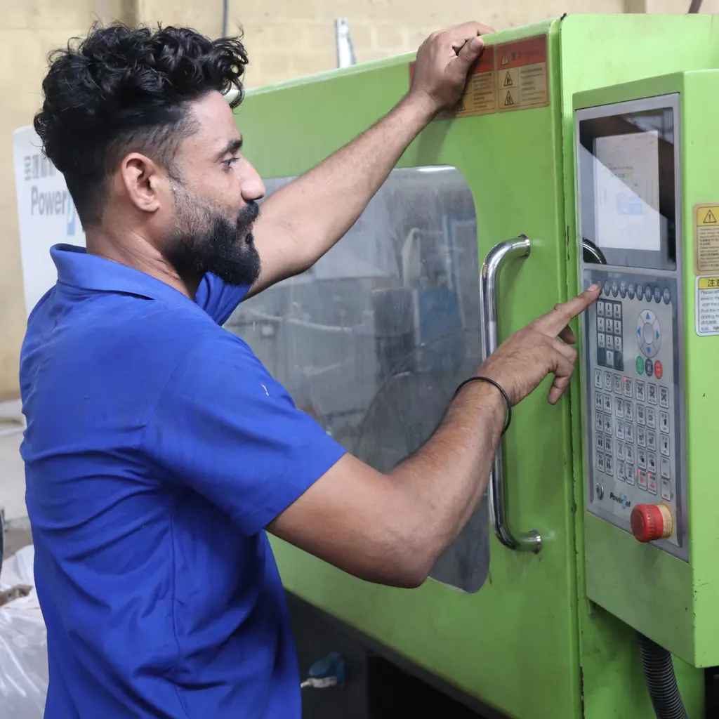An operator using the control panel of an enclosed molding machine.