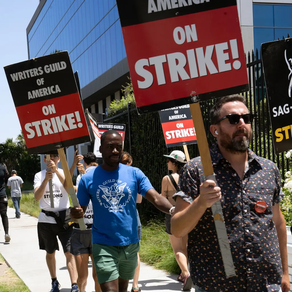 People carrying Writers Guild strike signs on a picket line.