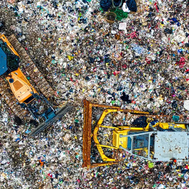 Earthmoving machines working across the active face of a landfill.