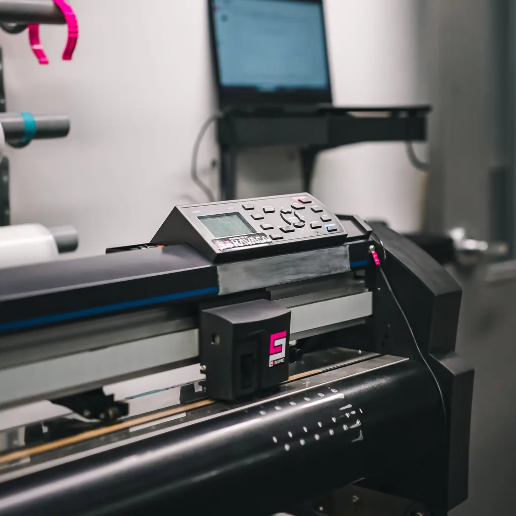 A roll-fed cutting plotter and material rolls in a print studio.