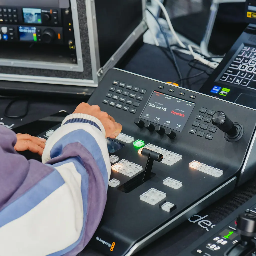 An operator working at a professional video switcher and control monitors.