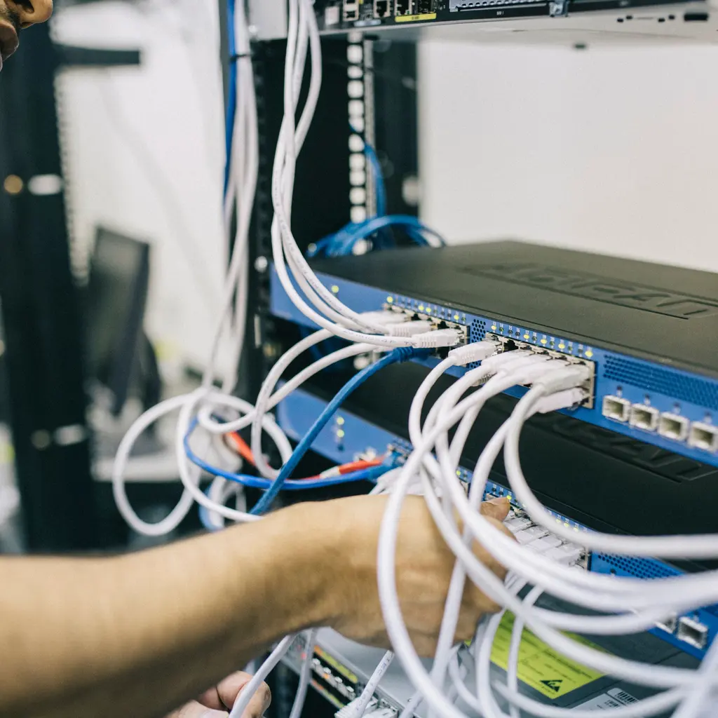 A technician working on network connections inside an equipment rack.