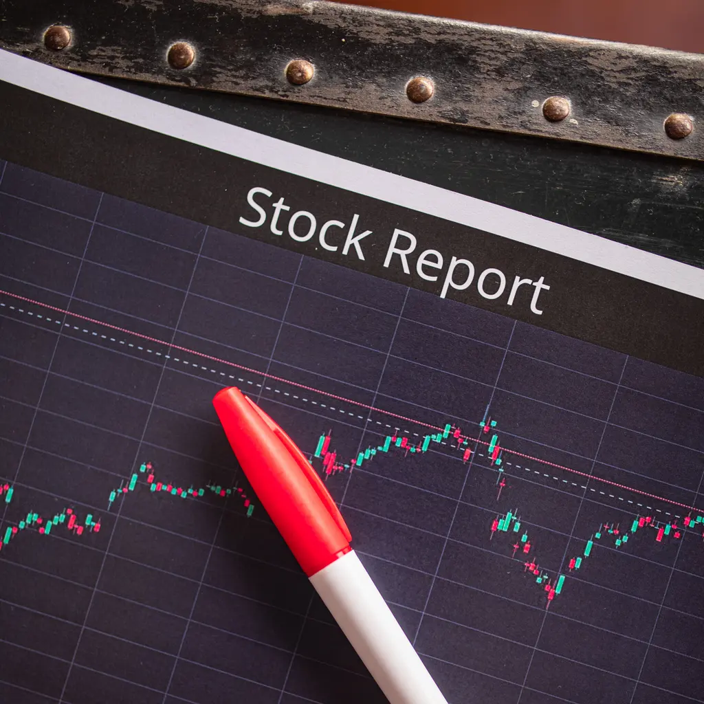 A printed stock-market price chart with a pen.