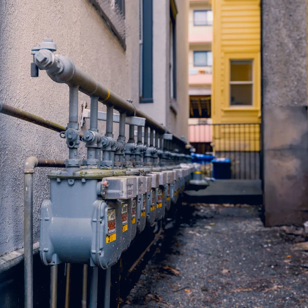 Gas meters and shutoff valves along a building exterior.