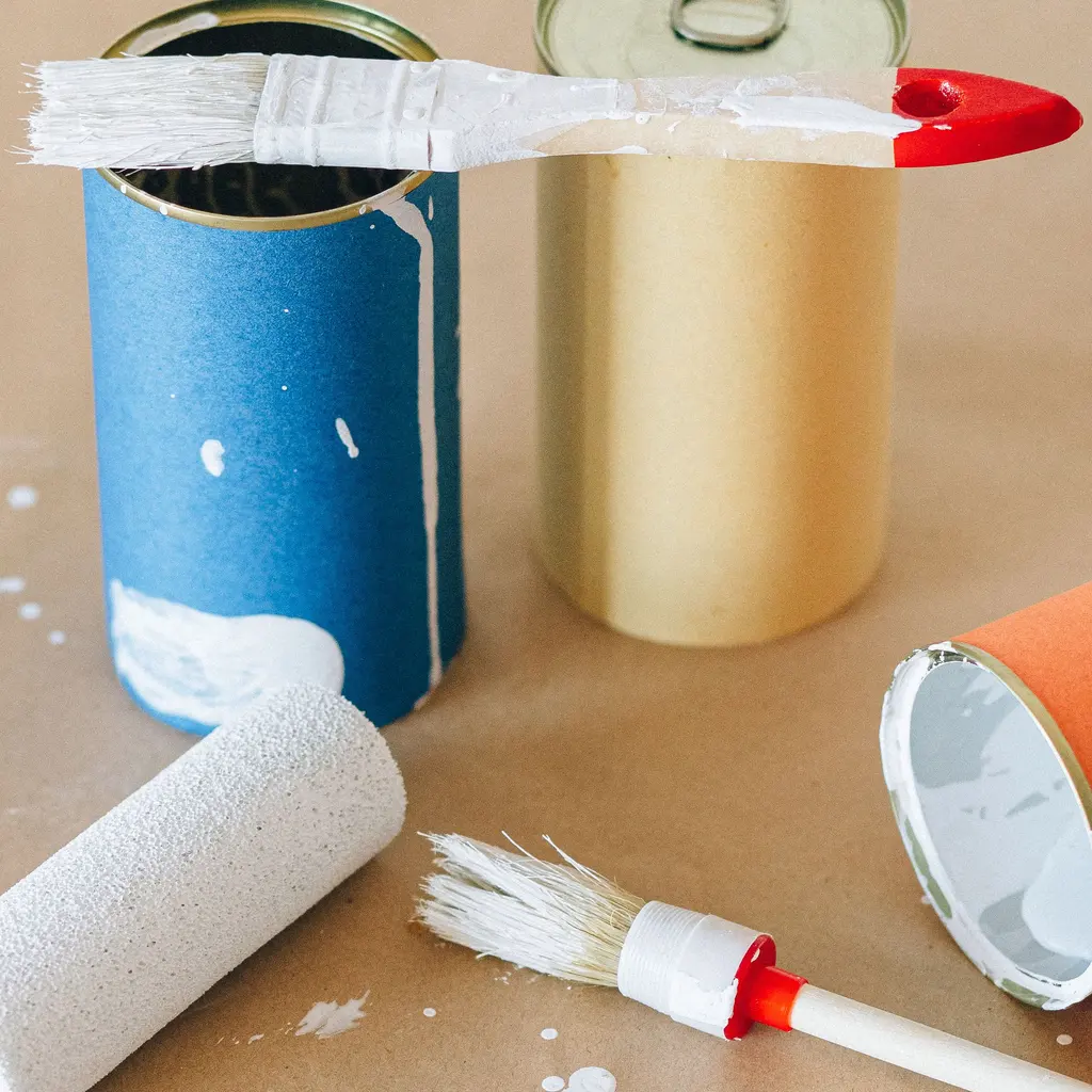 Open paint cans, brushes and a roller arranged on brown covering paper.