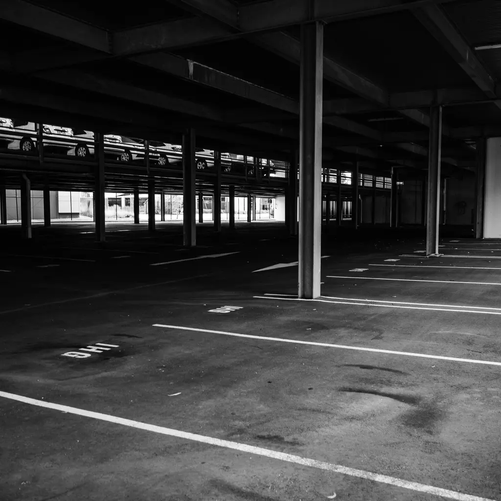 Marked parking bays beneath concrete columns in an empty covered parking garage.