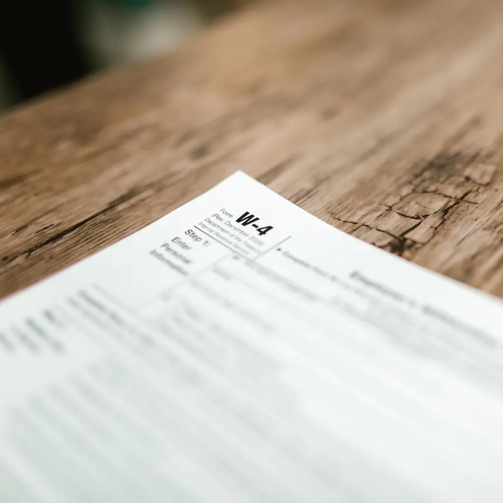 A Form W-4 employee withholding certificate on a wooden desk.