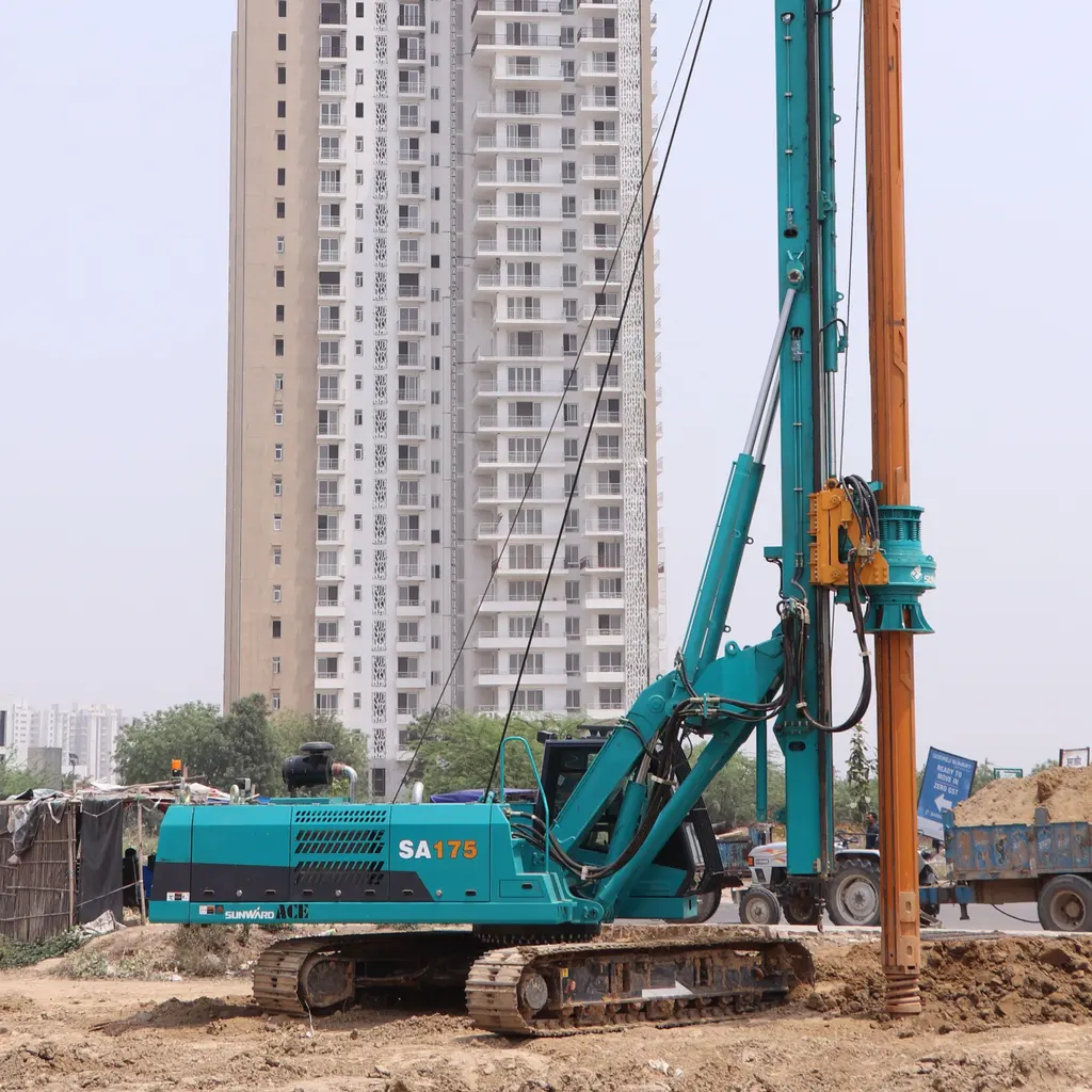 Tracked rotary piling rig boring into soil at an urban construction site.