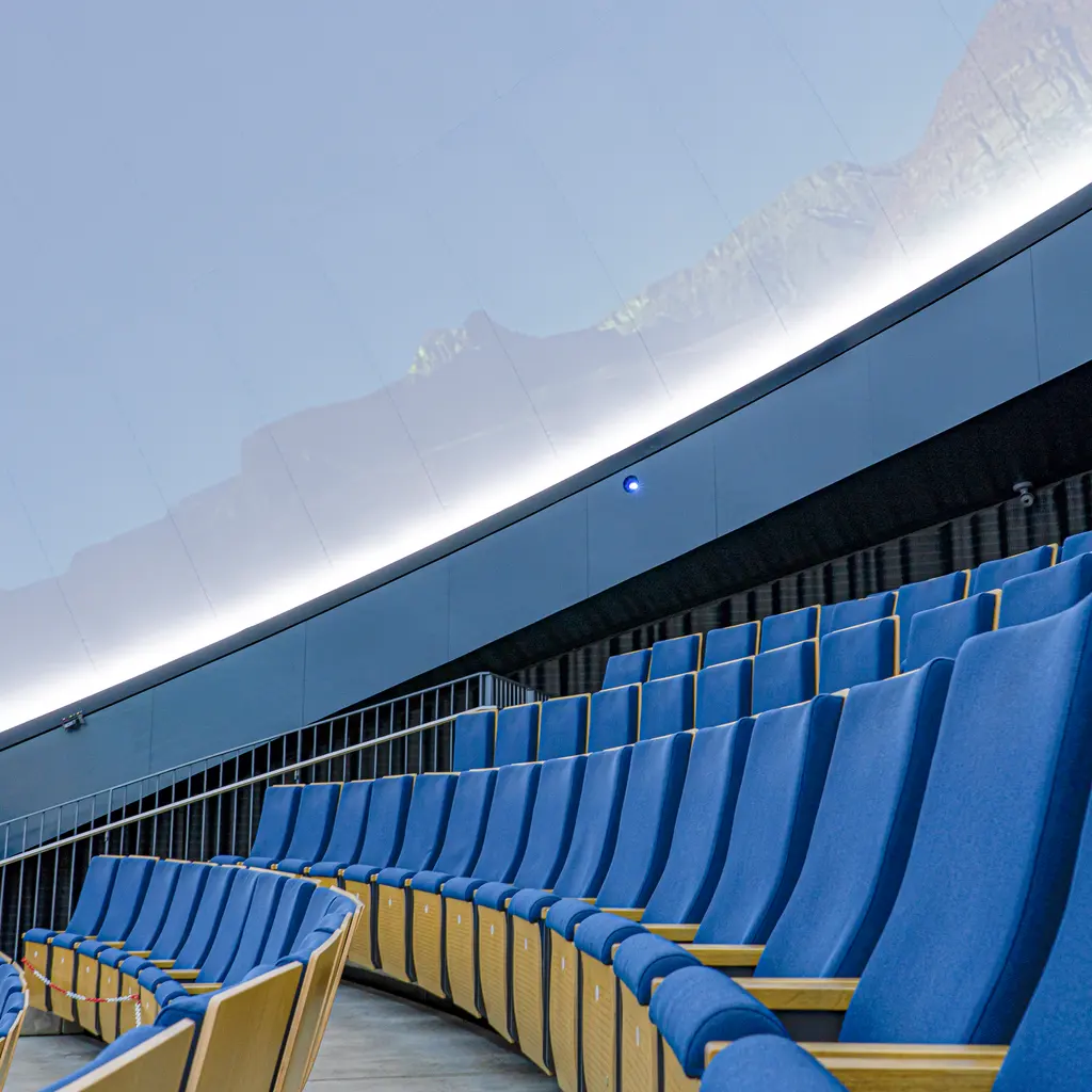 Empty seating beneath the curved projection dome of a planetarium.