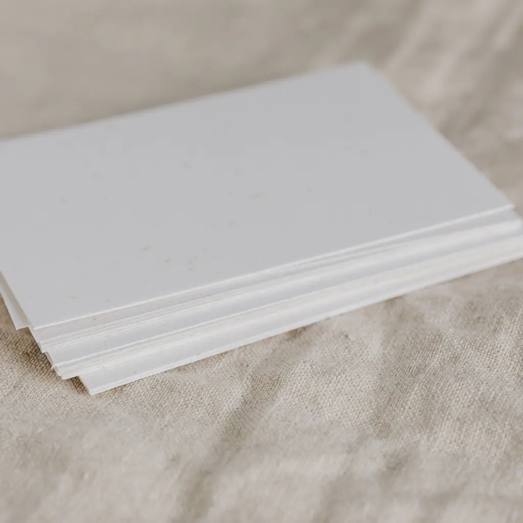 A stack of blank white paper sheets on a textured surface.