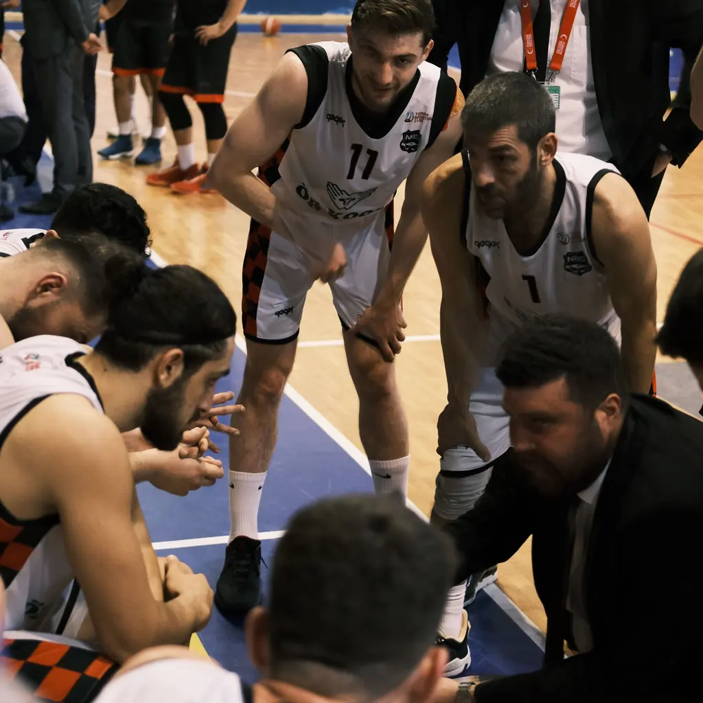 Adult basketball players listening to a coach in a courtside huddle.