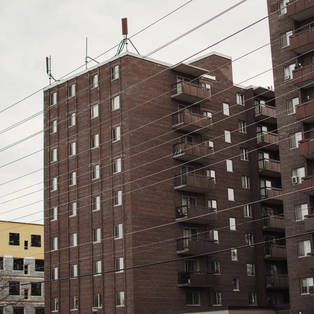 Brick apartment buildings with balconies and parking spaces.