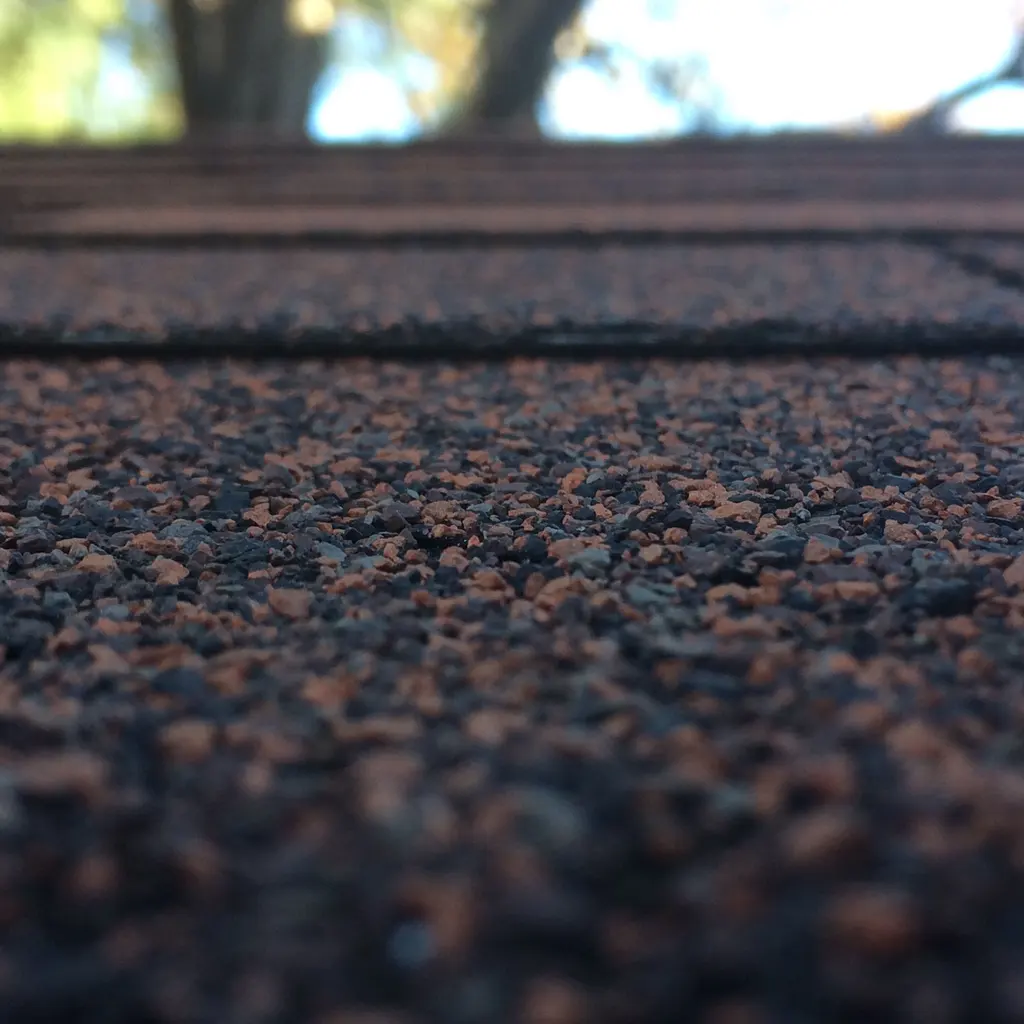 Overlapping asphalt roofing shingles with a mineral-granule surface.