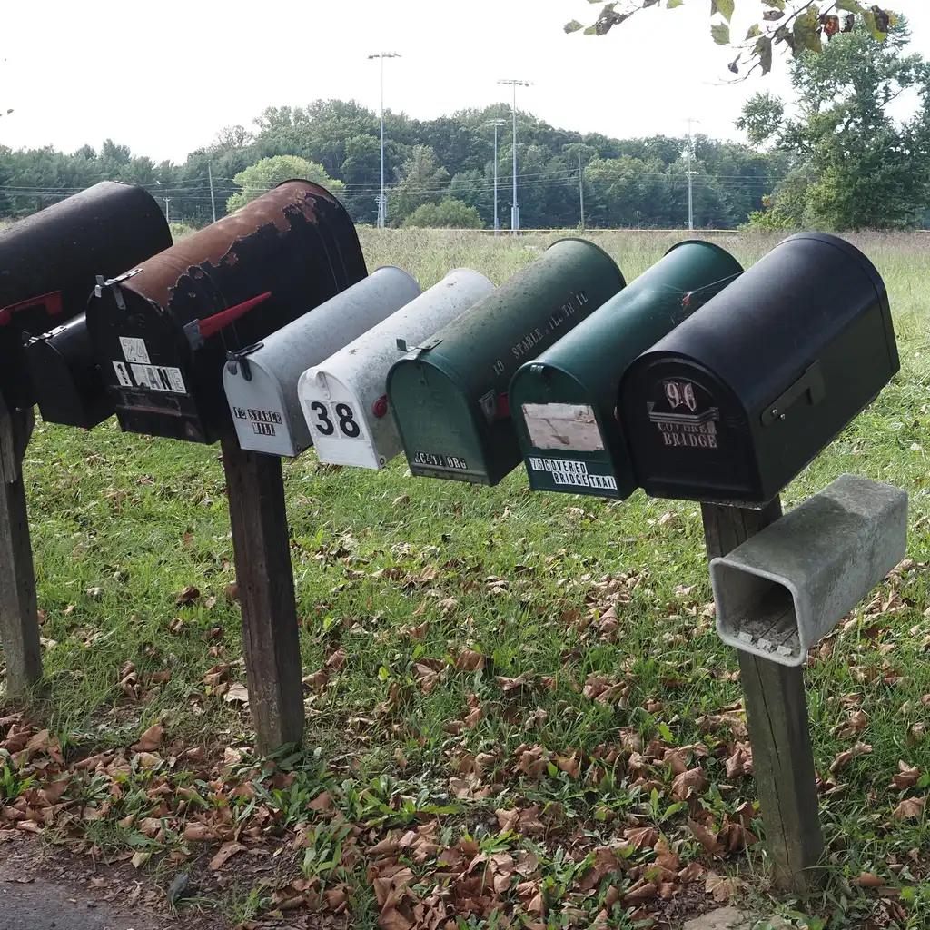 A row of roadside mailboxes beside an open rural field.