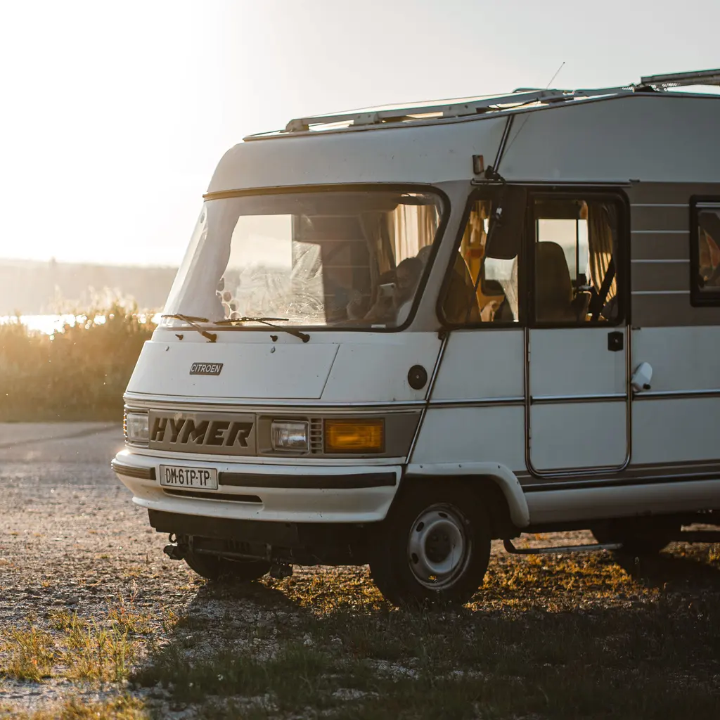 A motorhome parked on gravel in low evening light.