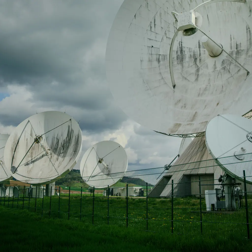 Several large satellite antennas within a fenced ground-station facility.