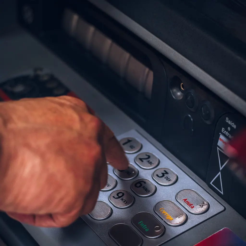 A hand using an ATM's numbered keypad.