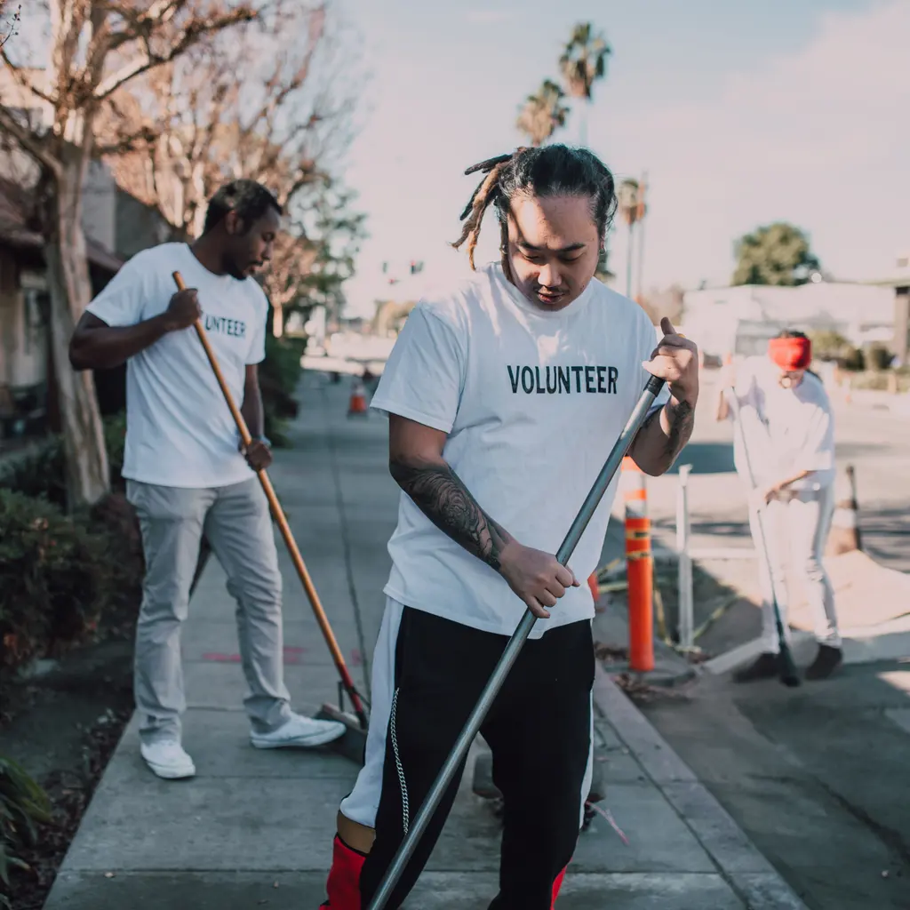 Volunteers sweeping a sidewalk during a community cleanup.