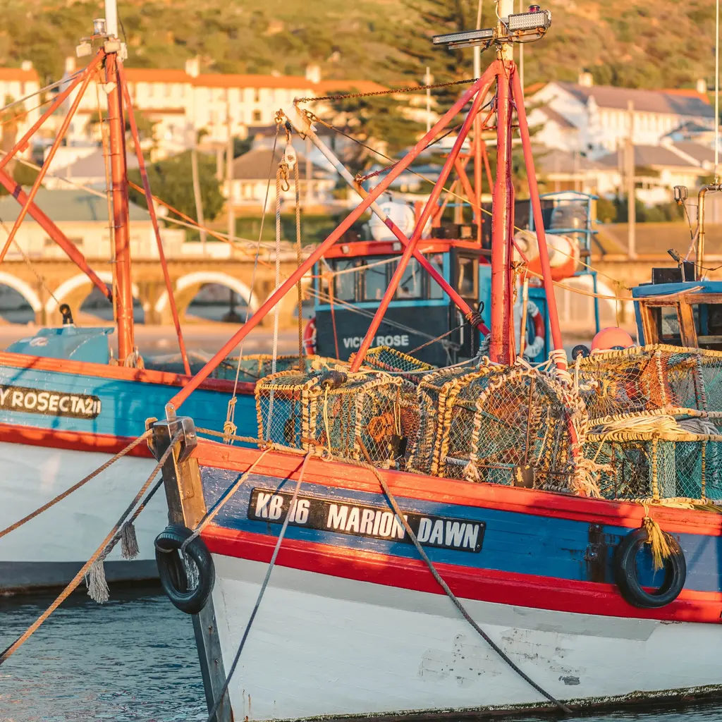 Lobster pots stacked aboard working fishing boats at a quay.