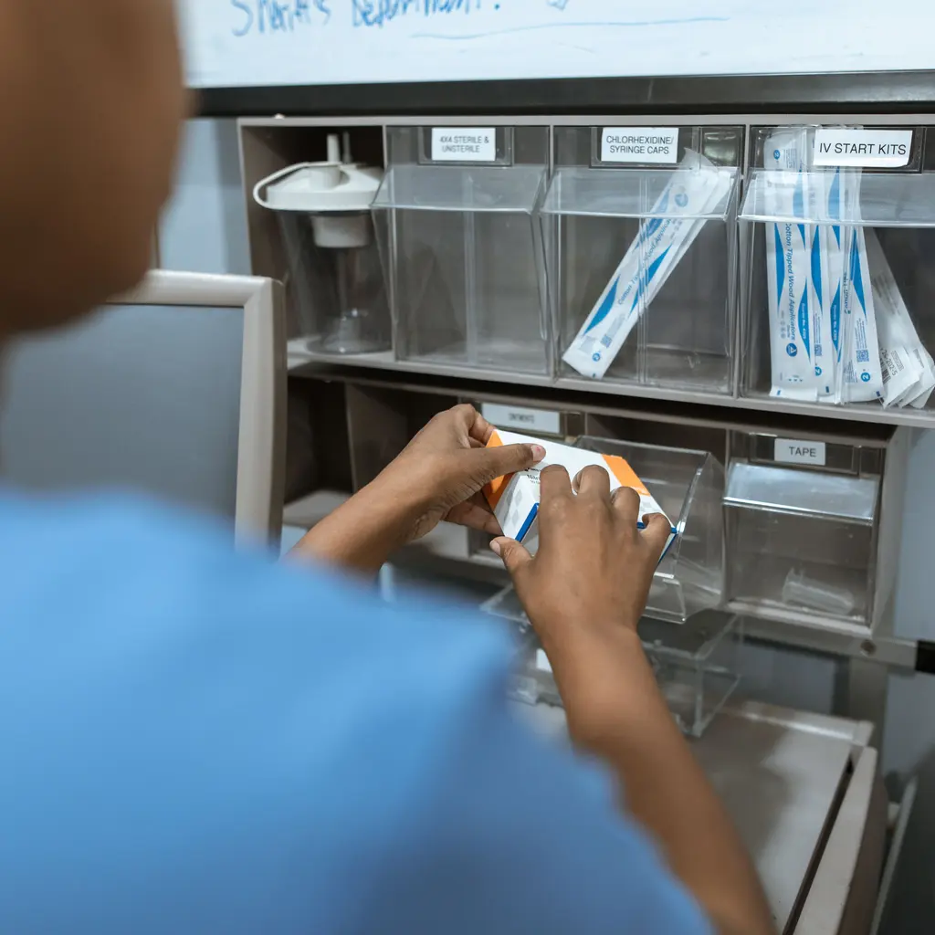 A nurse organizing clinical supplies in labeled storage drawers.
