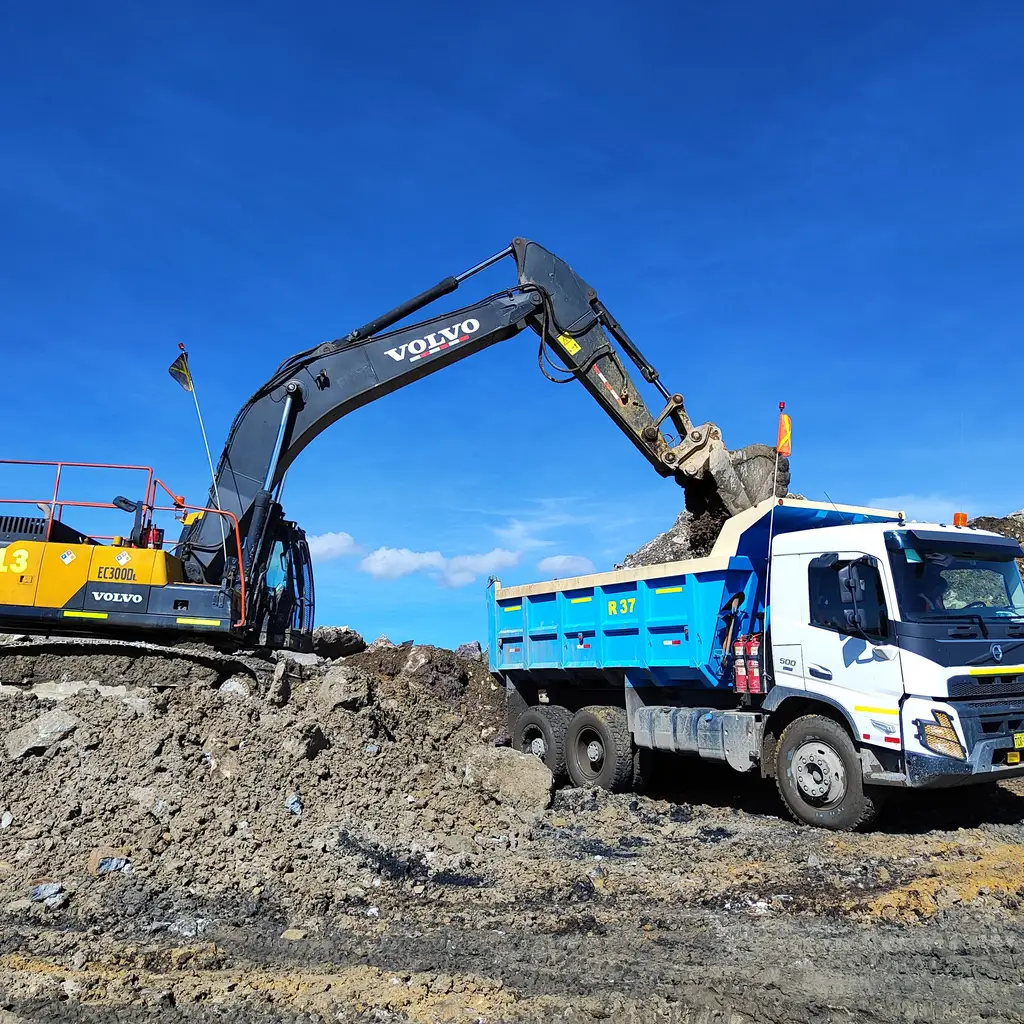 An excavator loading excavated material into a dump truck.
