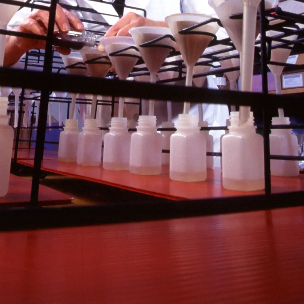 Laboratory funnels filtering soil samples into collection bottles.