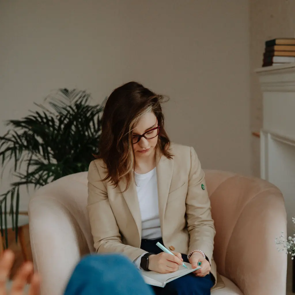 A counselor writing on a notepad during a conversation.