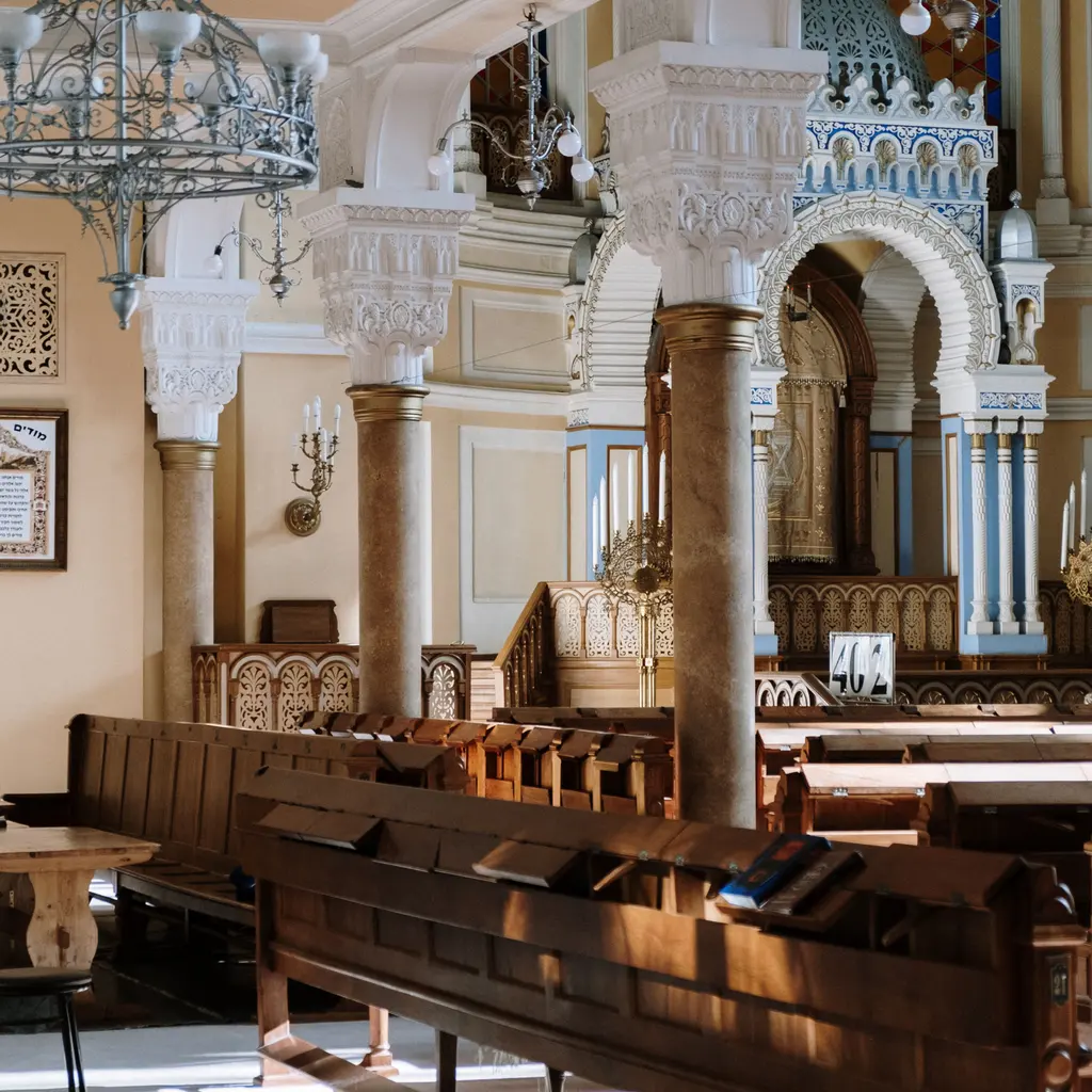Wooden pews facing an ornate Torah ark inside an empty synagogue.