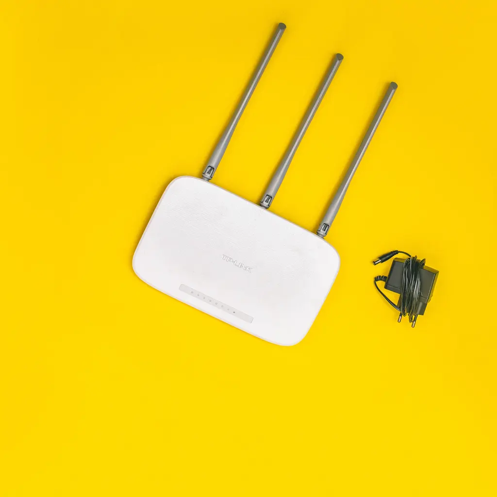 A white wireless router with three antennas and a power adapter.