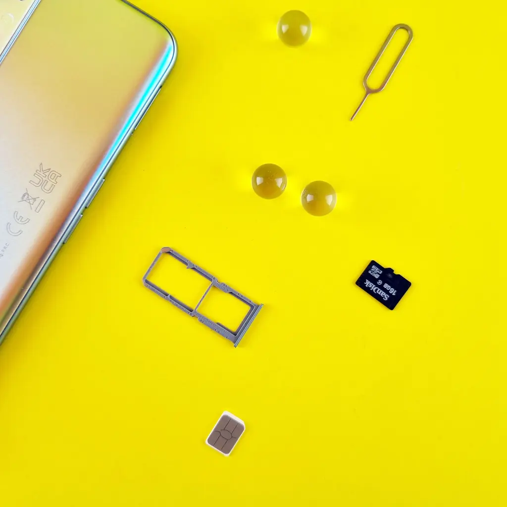 A SIM card and card tray beside a smartphone.