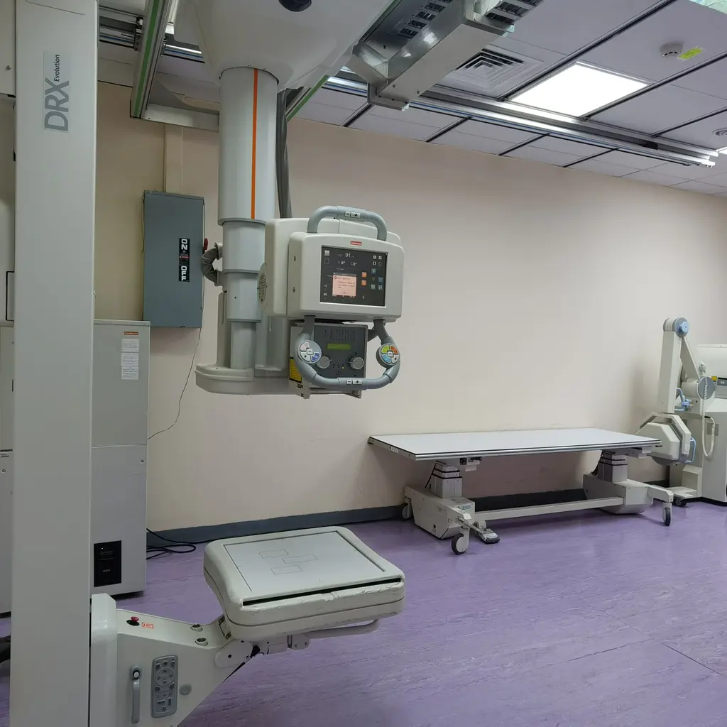 An unoccupied X-ray room with an imaging table and overhead equipment.