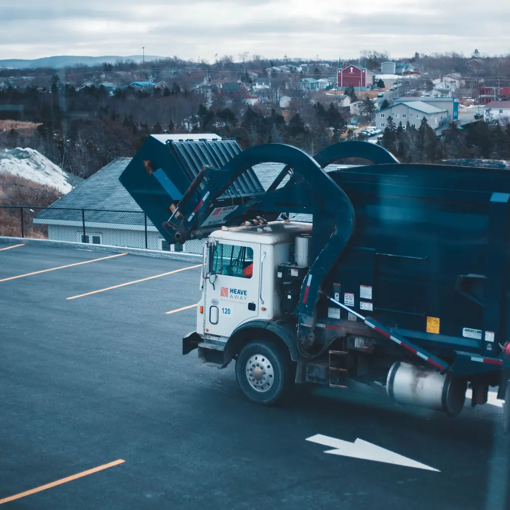 A front-loading refuse truck parked in a paved lot.