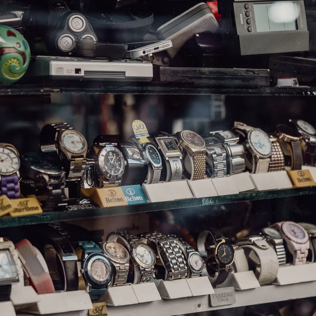 Wristwatches arranged on padded display stands inside a glass case.