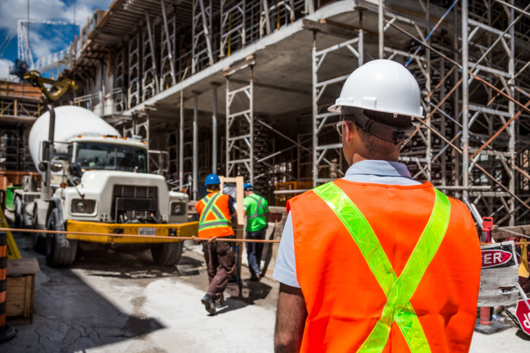 a man in safety vest and hardhats standing in front of a construction site