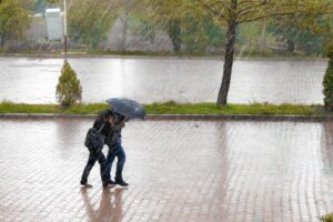 "Couple walking under an umbrella in rain, highlighting Back-to-School Health Insurance Tips for College Students."